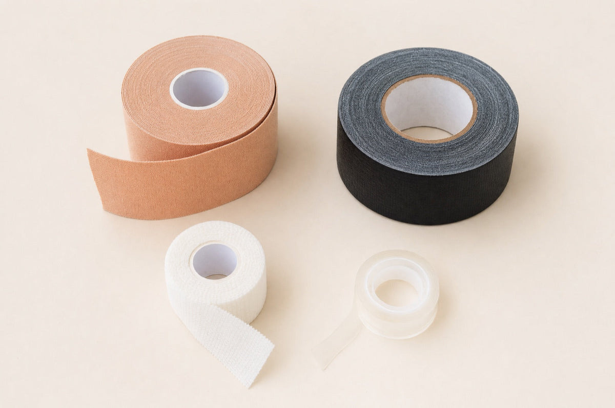 Flat lay of skin-tone body tape, black gaffer tape, sports tape and double-sided clothing tape